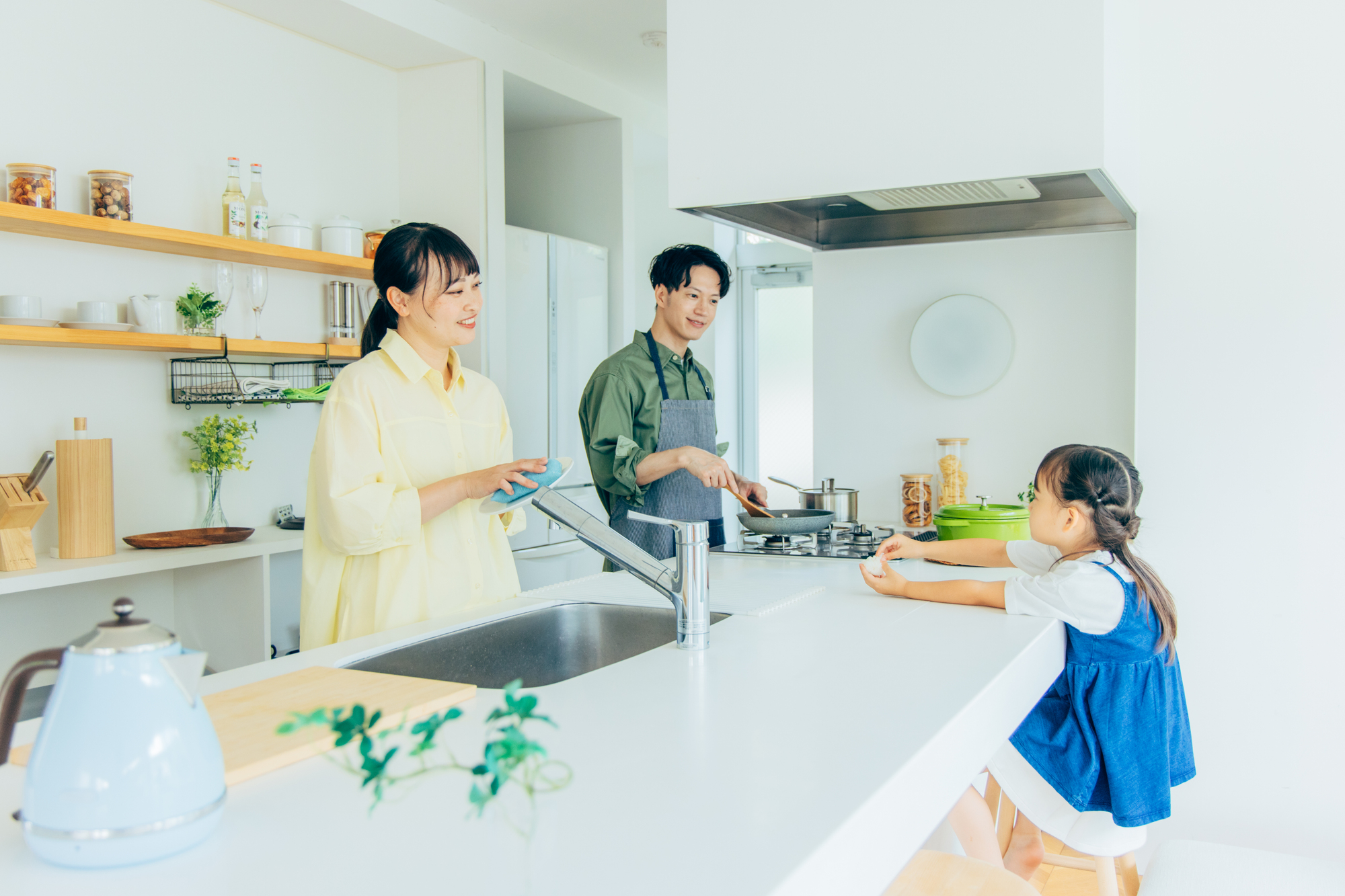 壁付けキッチンを対面式に変更し、真鍮色の照明と無垢床でまとめたリノベーション後のLDKを斜めから撮影した施工事例写真